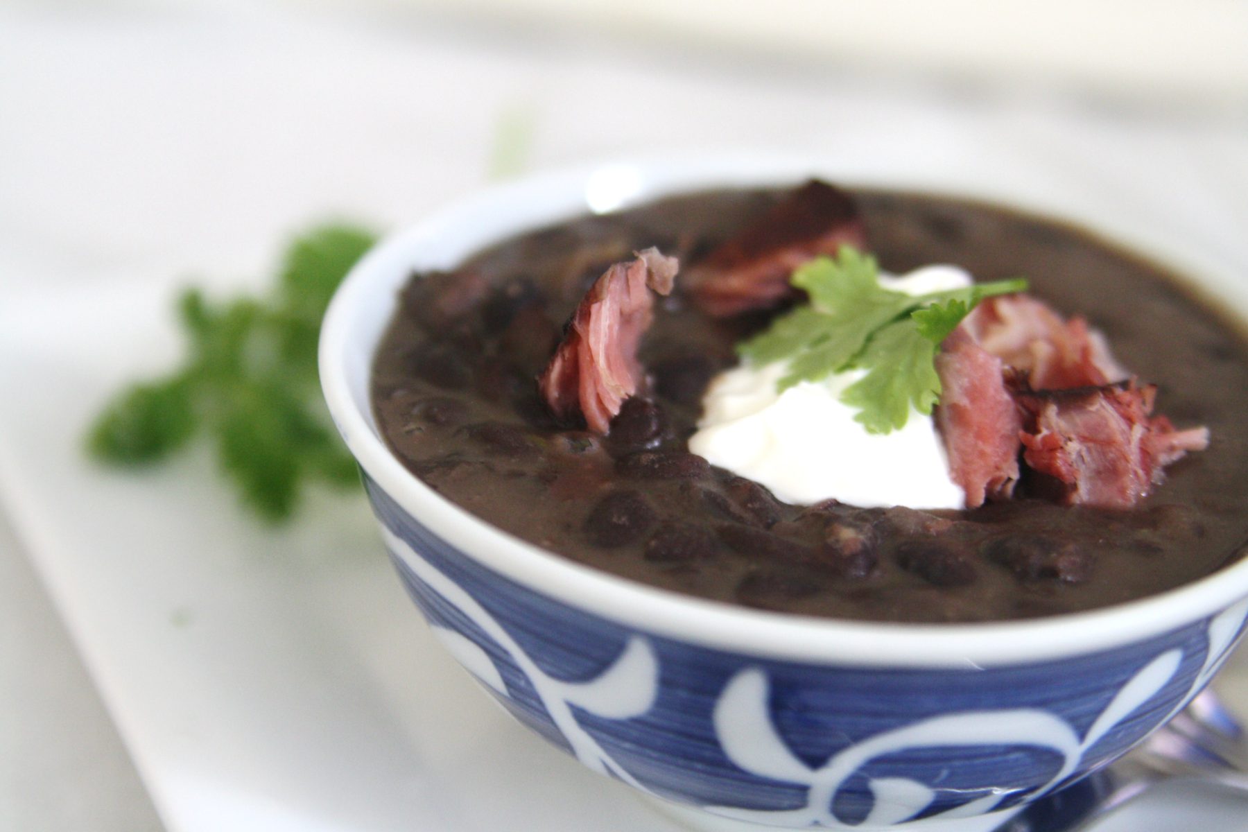 Cuban Black Bean Soup with Smoked Ham Hock is made with black beans simmered with smoked ham hocks and aromatic ingredients like onions, garlic, bell peppers, and spices. The infusion of flavors creates a deeply satisfying and robust soup.
